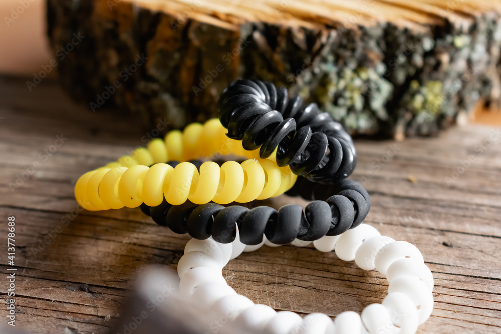 Fashionable and modern elastic hair springs. Different colors of stretching hand bracelets on wooden background, stand