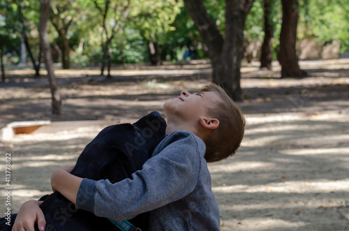 Dog licking boy who hugs her neck.