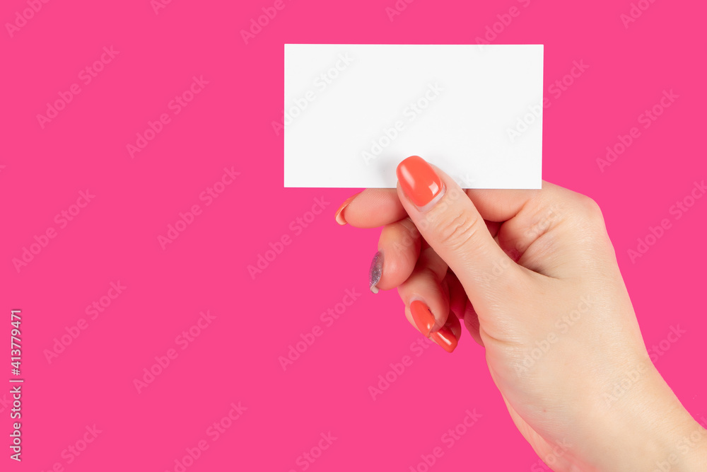 Hand holding paper business card on pink background Hand holding paper business card on pink background