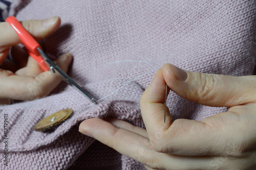 female workers' hands sew a wooden button to a jacket. close-up.