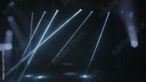 Colorful stage lights. White spotlights and laser holograms spins, turns and emits light bright beams. Lighting equipment and light effects for concert hall and stage lighting during show or disco. photo