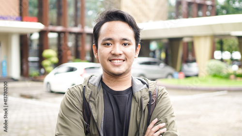Fényképezés Portrait of smiling Asian man with backpack standing and staring at the camera