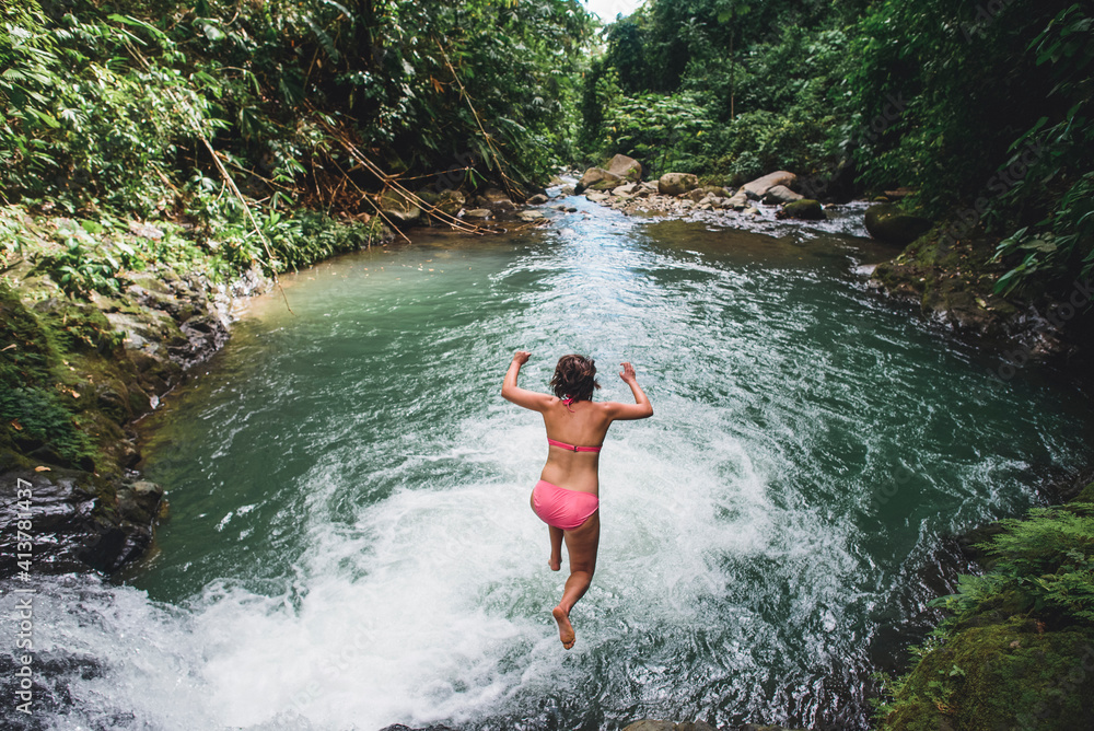 High angle view of carefree woman jumping into lake amidst forest High angle view of carefree woman jumping into lake amidst forest