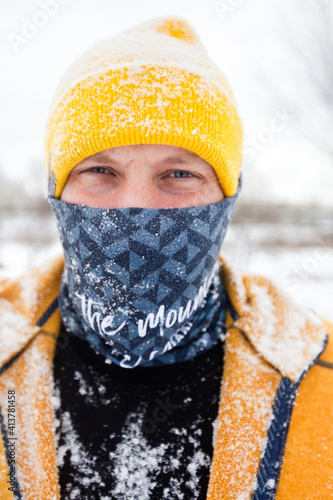 Foto A male runner, an athlete in a yellow cap, with a buff on his face, stands in a black thermal jacket and a yellow sweater