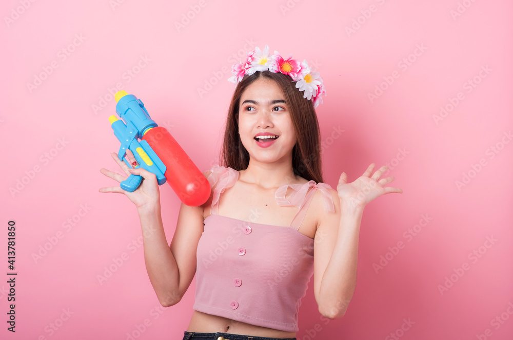 Young happy beauty Asian woman holding plastic water gun at Songkran festival, Thailand. Thai New Year's Day. Isolated on black background. Young happy beauty Asian woman holding plastic water gun at Songkran festival, Thailand. Thai New Year's Day. Isolated on black background.