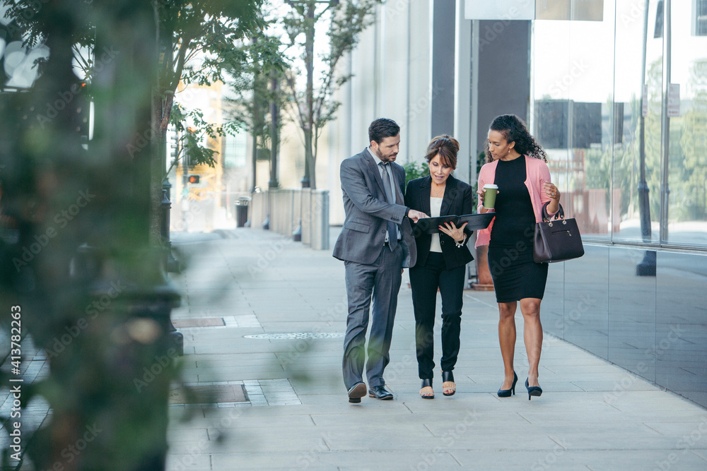 Business people discussing over documents while walking on footpath Business people discussing over documents while walking on footpath
