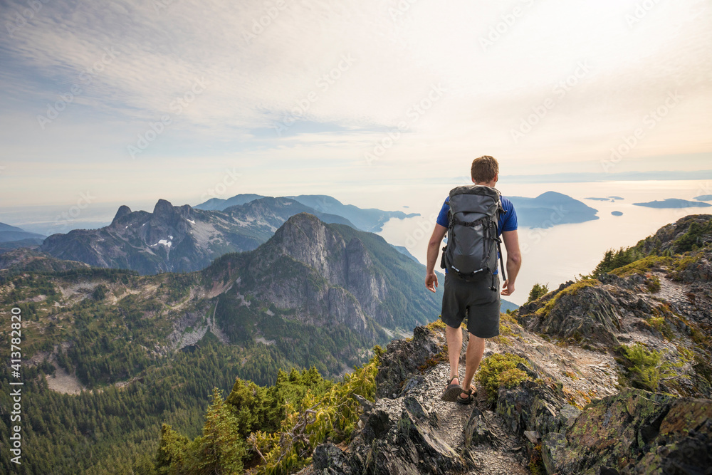 Rear view of carefree hiker with backpack walking on mountain against sky Rear view of carefree hiker with backpack walking on mountain against sky