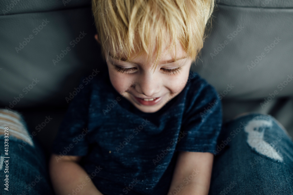 High angle view of smiling boy sitting on sofa at home High angle view of smiling boy sitting on sofa at home