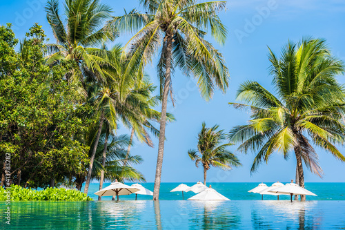 Fototapeta Naklejka Na Ścianę i Meble -  Umbrella and chair around outdoor swimming pool with coconut palm tree