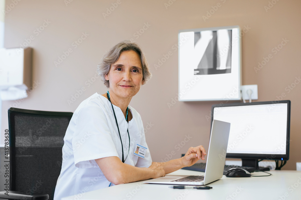Portrait of senior doctor working on laptop computer at hospital Portrait of senior doctor working on laptop computer at hospital