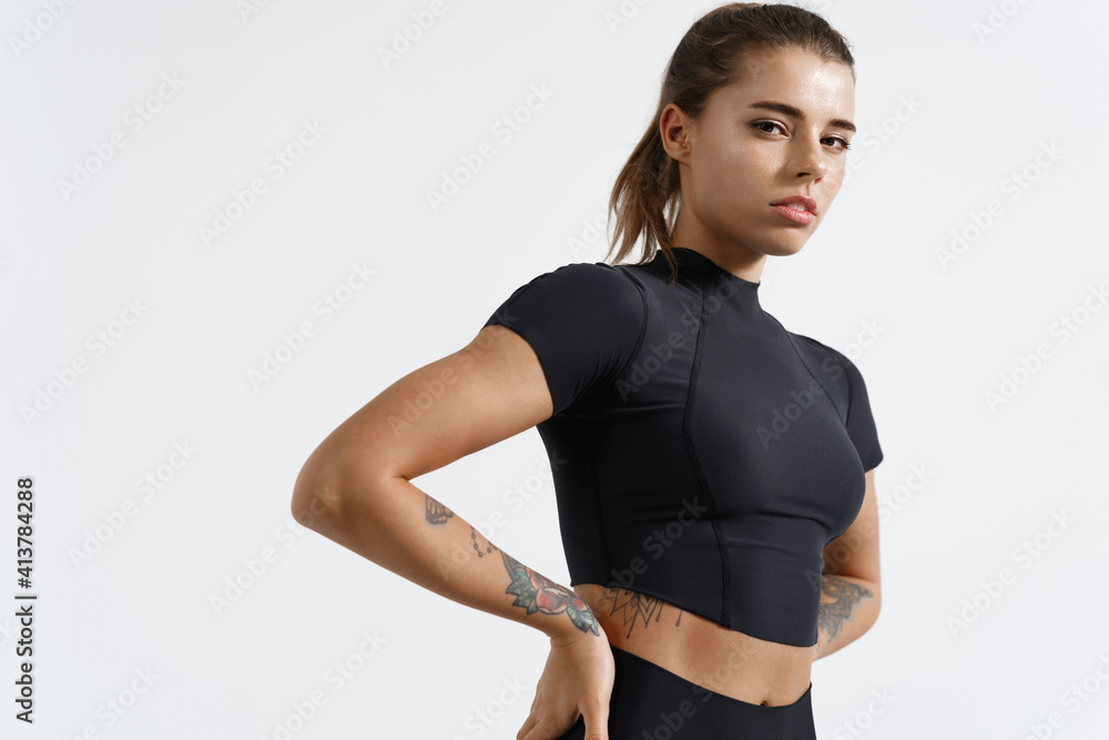© Liubov Levytska - Fitness woman looking confident at camera with hands on hips, exercising and workout on white background. Female athlete with fit body in sportswear training endurance