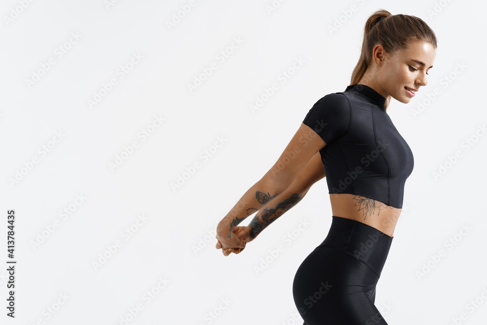 Foto de Fitness trained female stretching arms behind back, doing warm up  exercises. Woman runner with fit body do workout before jogging in  sportswear, white background do Stock