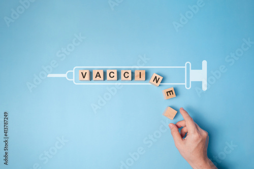 Text "VACCINE" on wooden block with syringe icon.