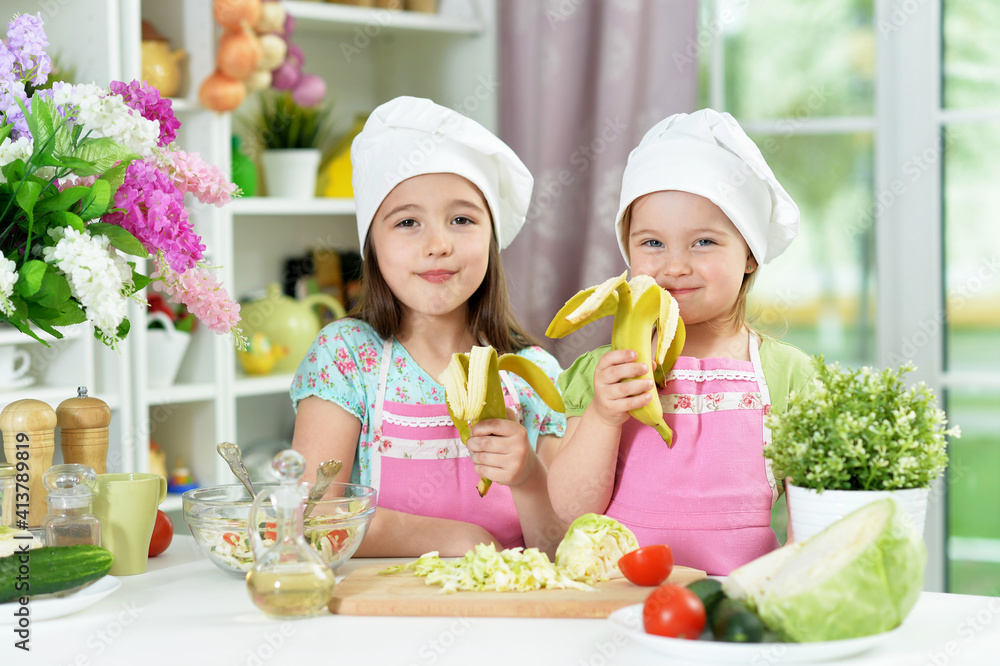 Cute girls eating bananas in kitchen Cute girls eating bananas in kitchen