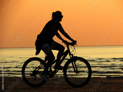 Fototapeta Naklejka Na Ścianę i Meble -  silhouette of a person riding a bike on sunset