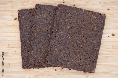 Three rectangular slices of pumpernickel bread on a wooden board photo