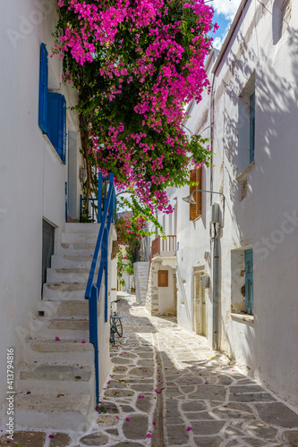 Traditional Cycladitic alley with a narrow street, whitewashed houses and a blooming bougainvillea in Parikia, Paros island, Greece. © valantis minogiannis