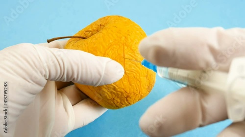 apple in genetic engineering laboratory with syringe and test tubes on blue background, gmo food concept