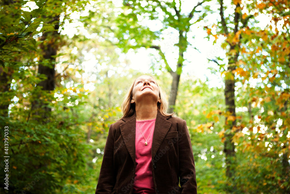 Senior woman looking up while standing against trees in Prospect Park Senior woman looking up while standing against trees in Prospect Park