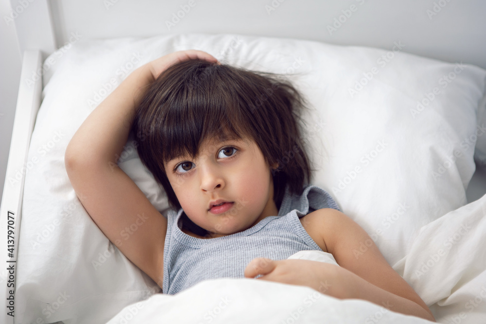 child boy lies in a white children's bed with a blanket in a room with toys rabbits child boy lies in a white children's bed with a blanket in a room with toys rabbits
