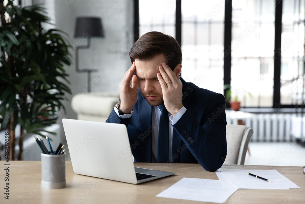 Unhealthy male employee sit at desk in office struggle from dizziness overwork on computer. Unwell tired Caucasian businessman work on laptop suffer from headache or migraine. Health problem concept. Unhealthy male employee sit at desk in office struggle from dizziness overwork on computer. Unwell tired Caucasian businessman work on laptop suffer from headache or migraine. Health problem concept.