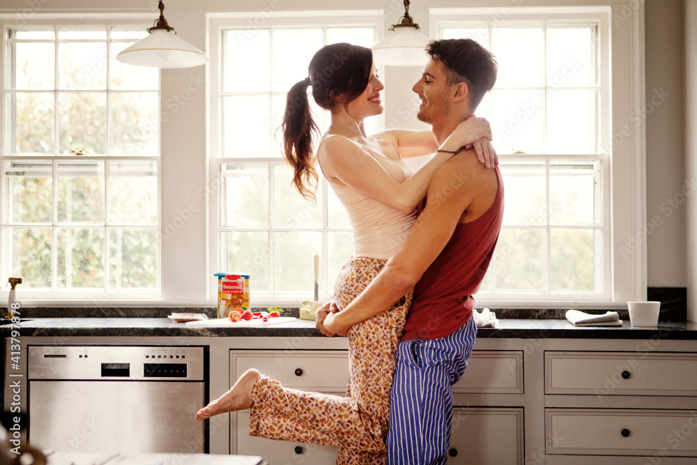 Happy couple embracing while standing in kitchen at home Happy couple embracing while standing in kitchen at home