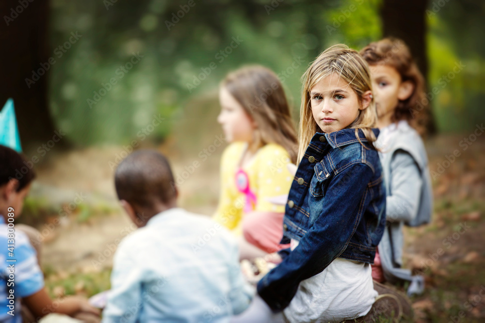 Portrait of girl sitting with friends on field at park Portrait of girl sitting with friends on field at park