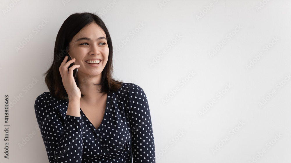 Overjoyed millennial asian female talking chatting on mobile phone holding gadget to ear. Young vietnamese woman involved in pleasant phone conversation. Studio shot on white background. Copy space Overjoyed millennial asian female talking chatting on mobile phone holding gadget to ear. Young vietnamese woman involved in pleasant phone conversation. Studio shot on white background. Copy space
