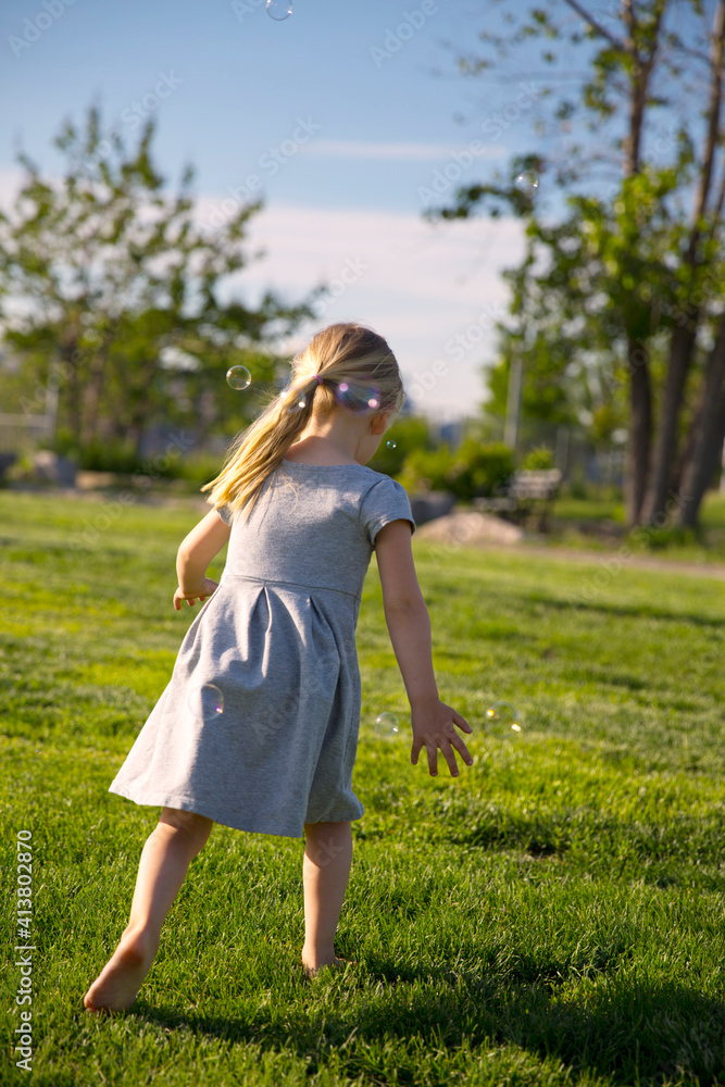 Rear view of girl walking on field at park Rear view of girl walking on field at park