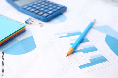 Close up of blue calculator and financial chart on table.