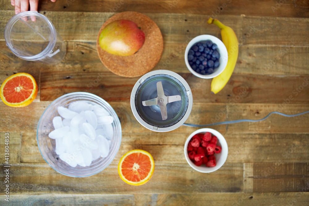 Overhead view of blender with fruits and containers on table Overhead view of blender with fruits and containers on table