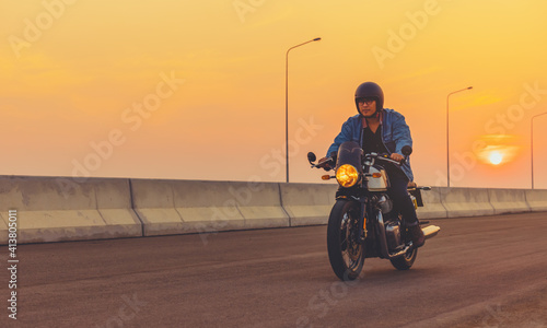 Foto Young man riding big bike motocycle on asphalt high way against at sunset