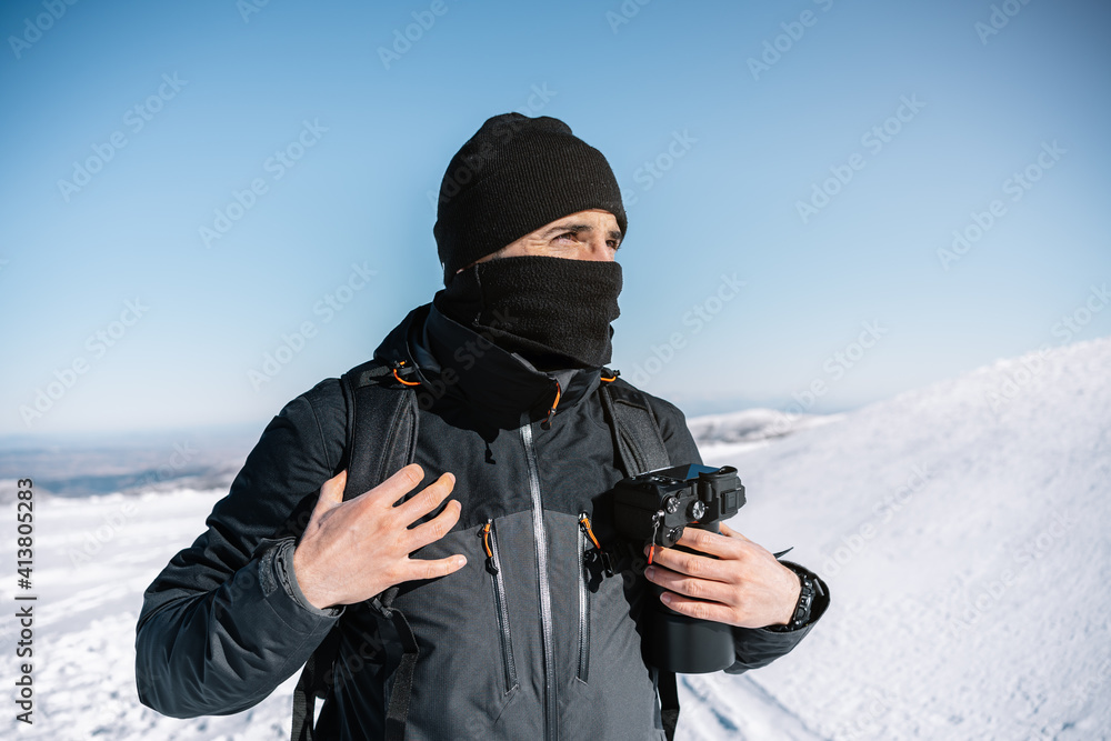 Portrait of an attractive photographer in the snow with professional camera in his backpack while walking. Portrait of an attractive photographer in the snow with professional camera in his backpack while walking.