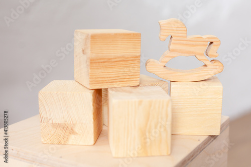 Fototapeta Naklejka Na Ścianę i Meble -  Wooden cubes and a horse for children's games. Child development. Security. Classes with a child. No plastic. Ecology and naturalness. Childhood. Close-up in natural tones.