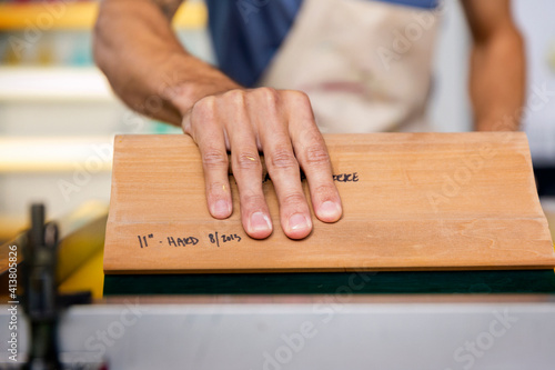 Close-up of hand pulling squeegee while working in workshop