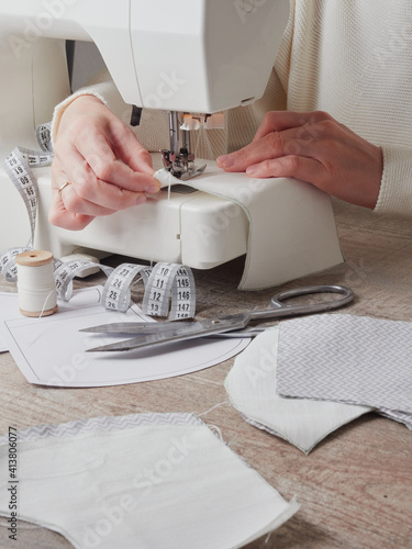 Sewing process, close up seamstress hands sew white clothes with sewing machine.