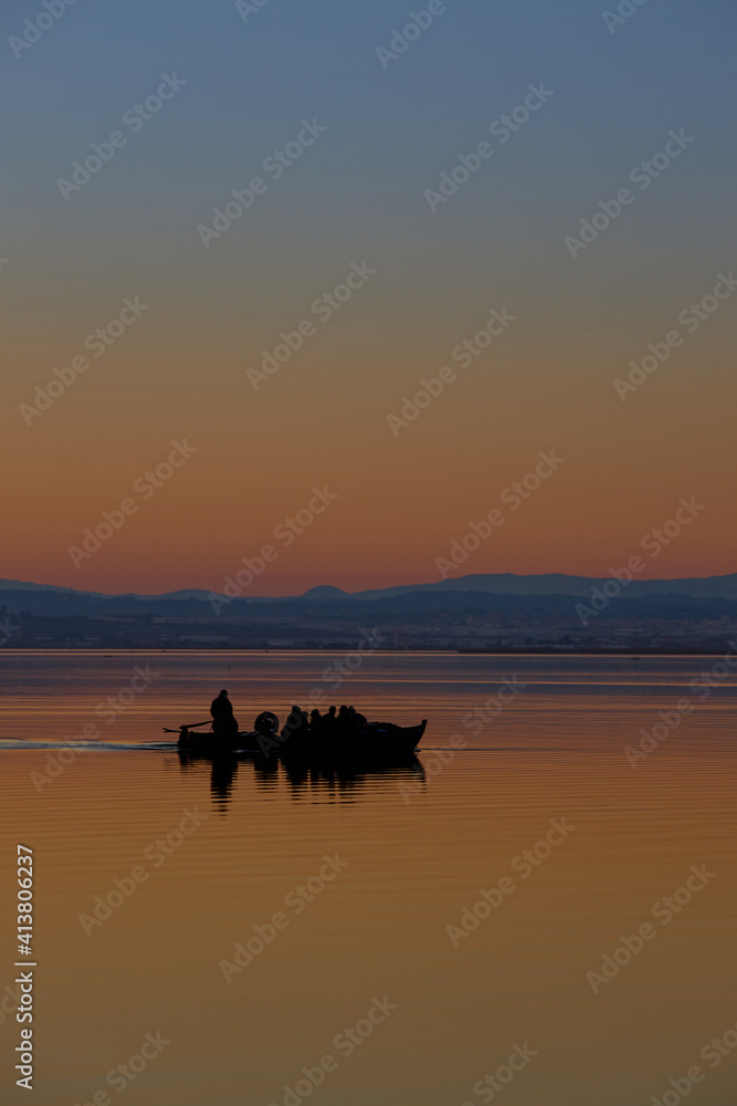 tourist boat with people in Valencia lagoon in Spain. sunset sky