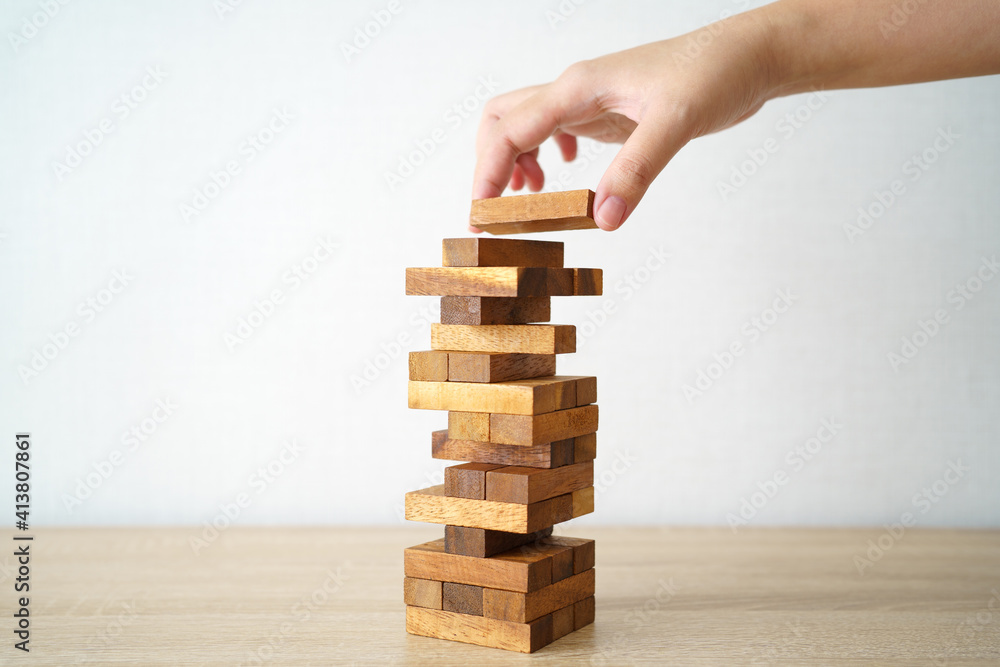 The risk will happen.Hand of engineer playing a blocks wood game on wood table vintage tone. architectural project .as background business concept with copy space. The risk will happen.Hand of engineer playing a blocks wood game on wood table vintage tone. architectural project .as background business concept with copy space.