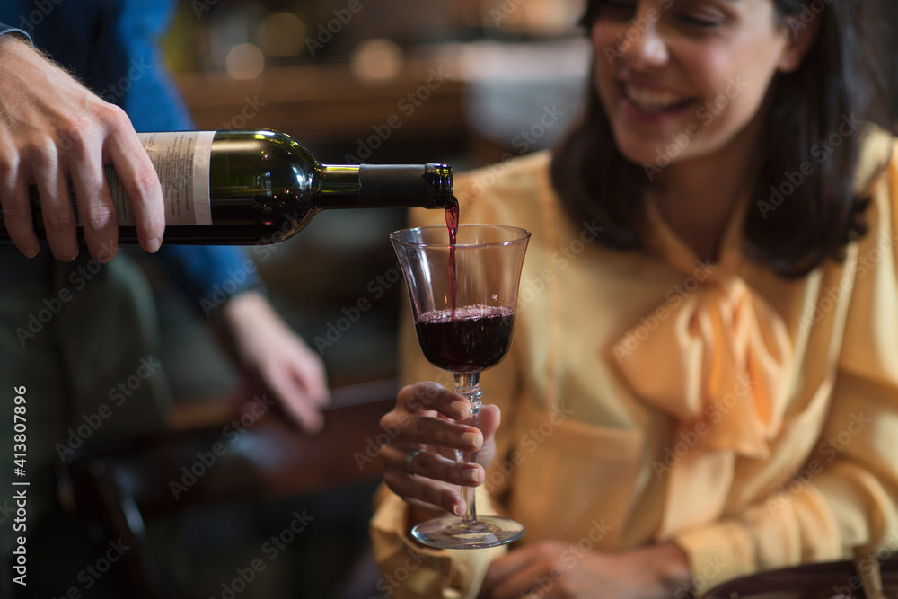 Man pouring wine to woman during Christmas party Man pouring wine to woman during Christmas party