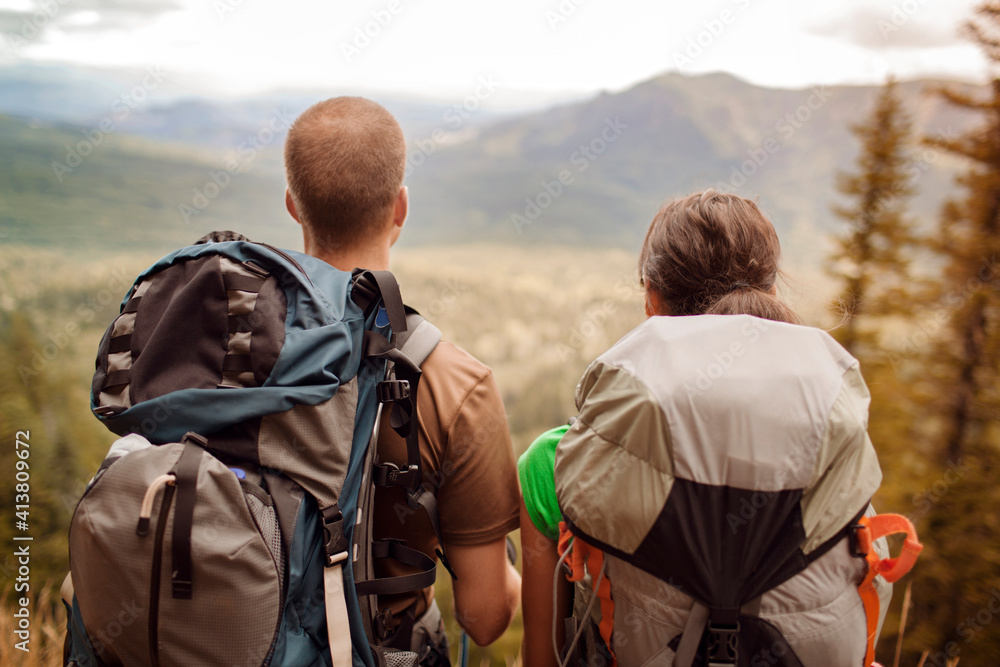 Rear view of couple carrying backpacks while looking at mountains Rear view of couple carrying backpacks while looking at mountains