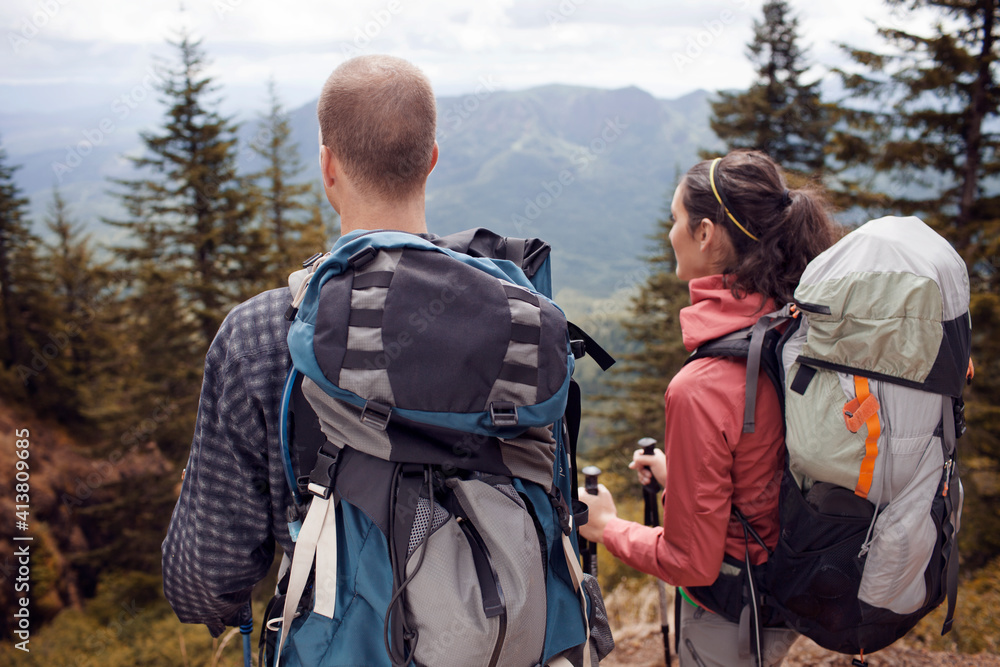Hikers carrying backpacks while looking at mountains Hikers carrying backpacks while looking at mountains