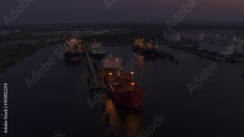 Sun setting over Antwerp industrial harbor with some oil and gas ships in night modus operandi photo