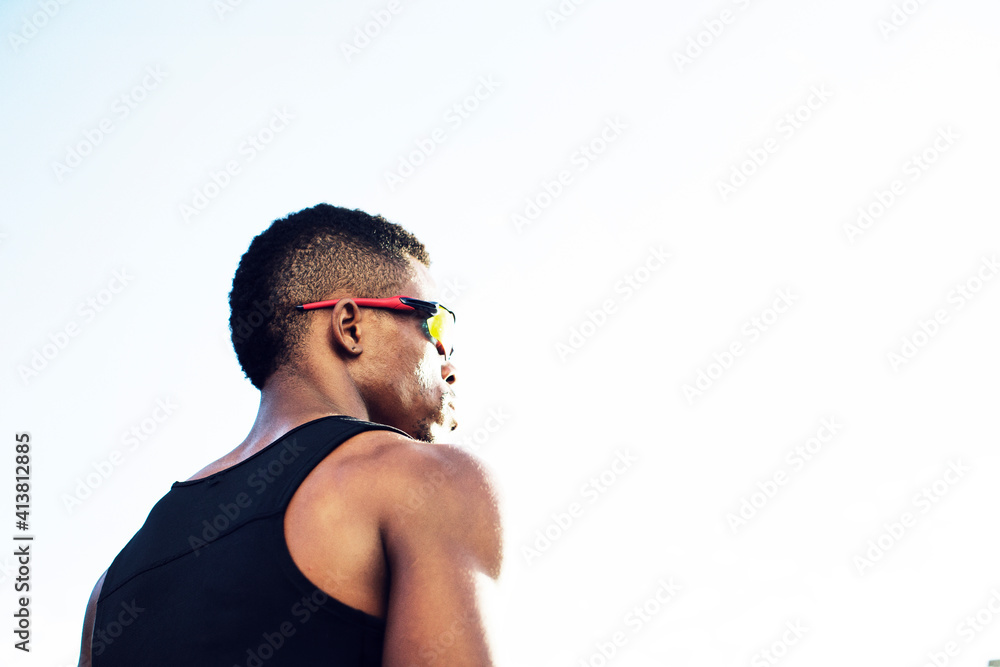 Low angle view of male athlete wearing sunglasses against clear sky Low angle view of male athlete wearing sunglasses against clear sky