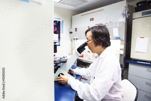 Wallpaper Mural Side view of senior female scientist using microscope Torontodigital.ca