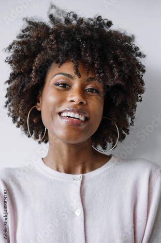 Beautiful black woman with afro hair smiling on the white background © sashapritchard