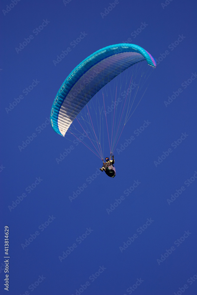 Low angle view of man paragliding in clear blue sky Low angle view of man paragliding in clear blue sky