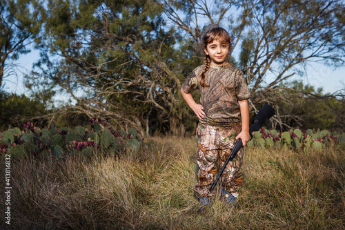 Portrait of girl with rifle on grassy field photo