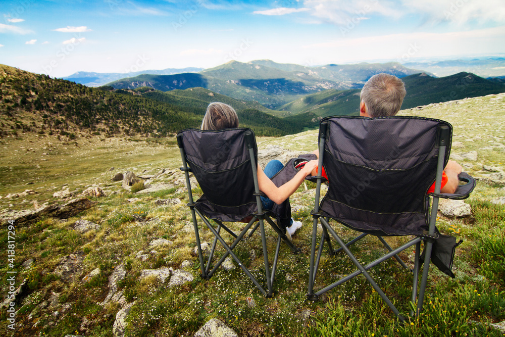 Rear view of couple sitting on chair against mountain Rear view of couple sitting on chair against mountain