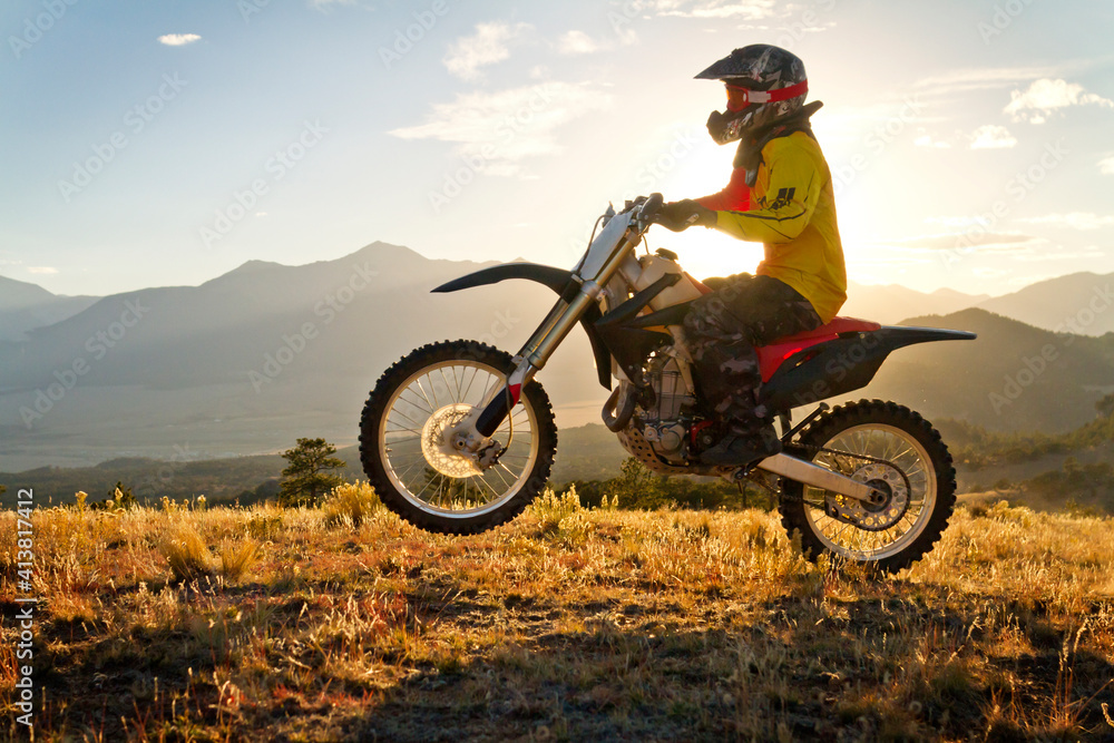 Biker riding dirt bike on grassy field against sky Biker riding dirt bike on grassy field against sky