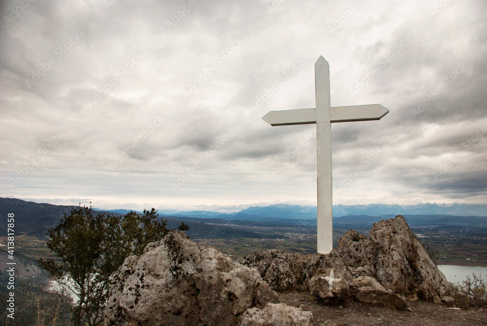 Cross on rock against cloudy sky Cross on rock against cloudy sky